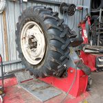 A large tractor tyre mounted on a heavy-duty tyre changer in a workshop